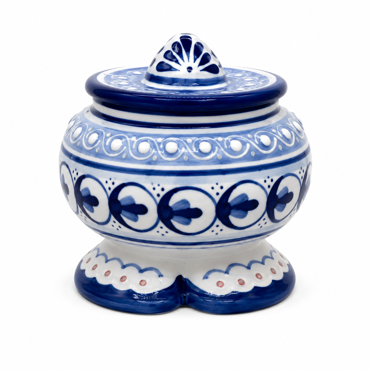 A traditional hand-painted ceramic jar with a lid, featuring a white base decorated with deep cobalt blue patterns, including floral motifs, scalloped borders, and a fan-shaped finial on top, set against a plain white background.