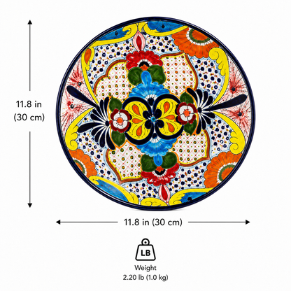 Round hand-painted ceramic plate with a vibrant Mexican Talavera style design, shown with dimension arrows indicating a diameter of 11.8 inches (30 cm) and a weight icon showing 2.